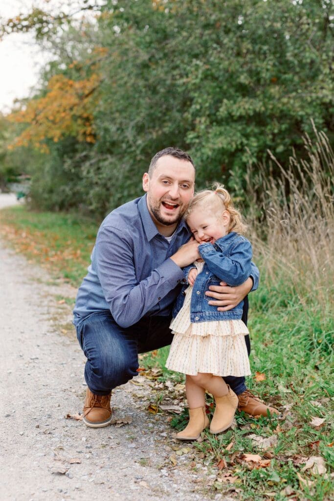 Father crouching down to hug and kiss his daughter during a walk