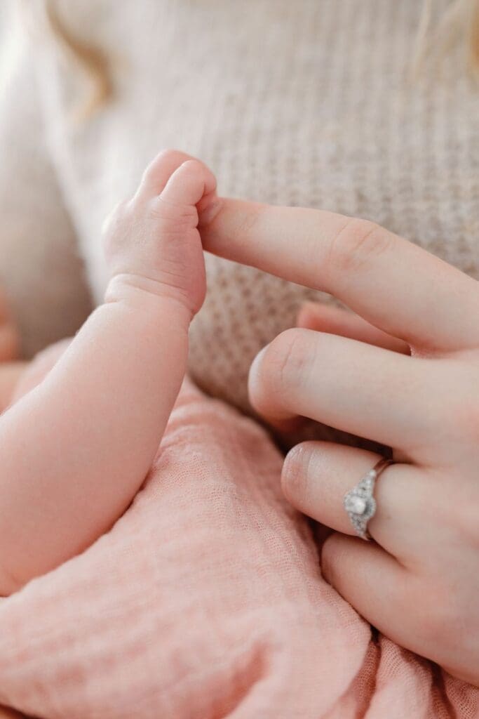 Close-up of a newborn grasping her parent’s finger
