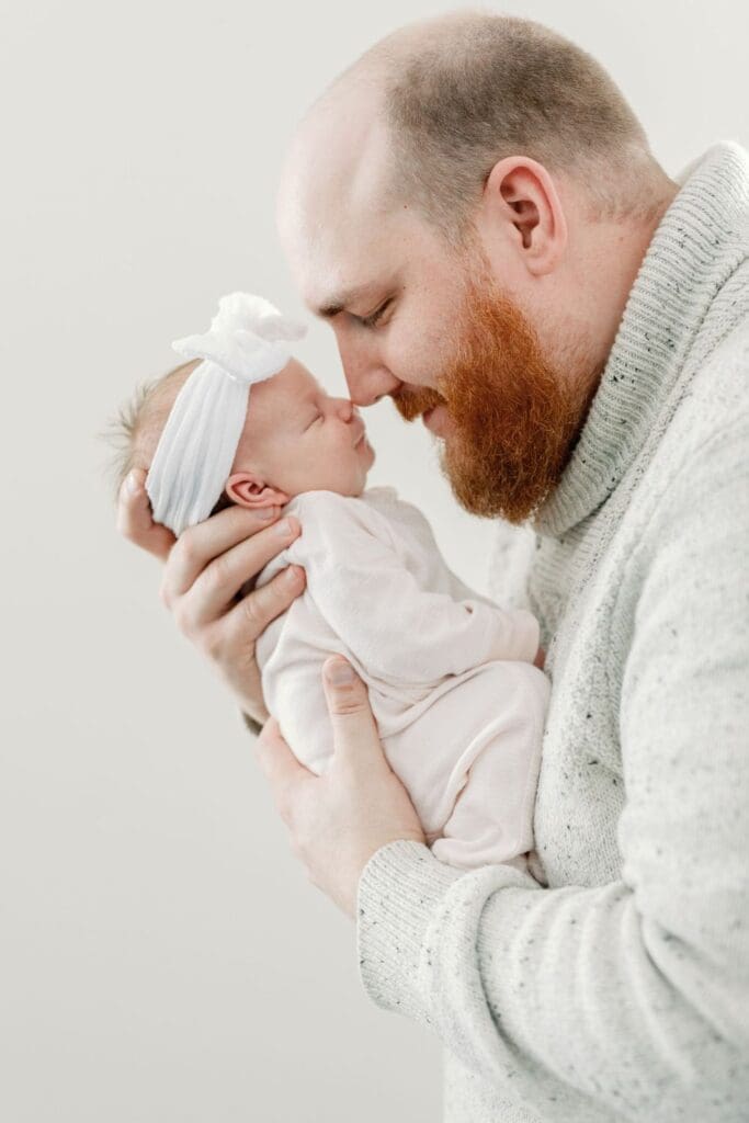 Father kissing his newborn daughter on the forehead while holding her close.