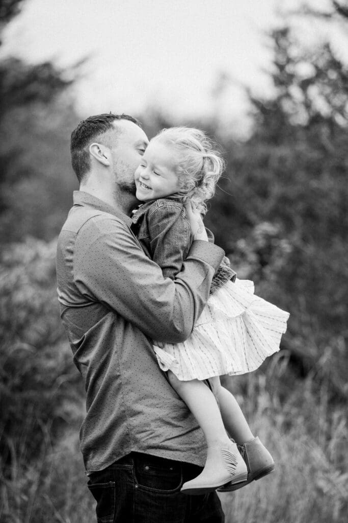 Father holding his daughter and lifting her in a loving hug.