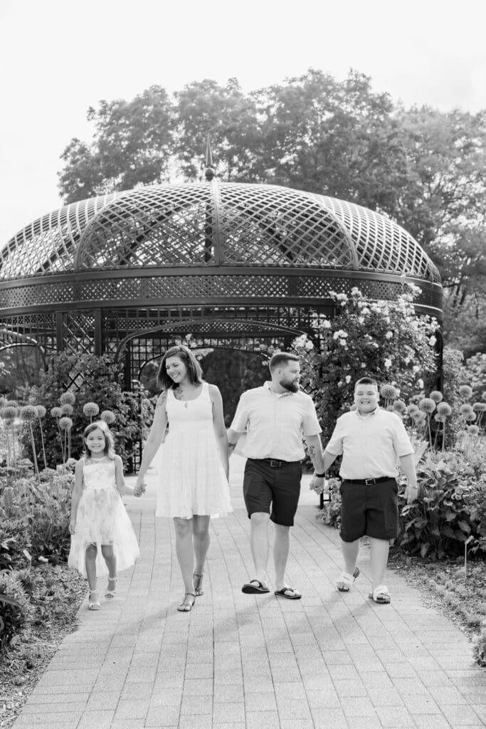 Family walking hand-in-hand near iron gazebo in Burlington Botanical Gardens.