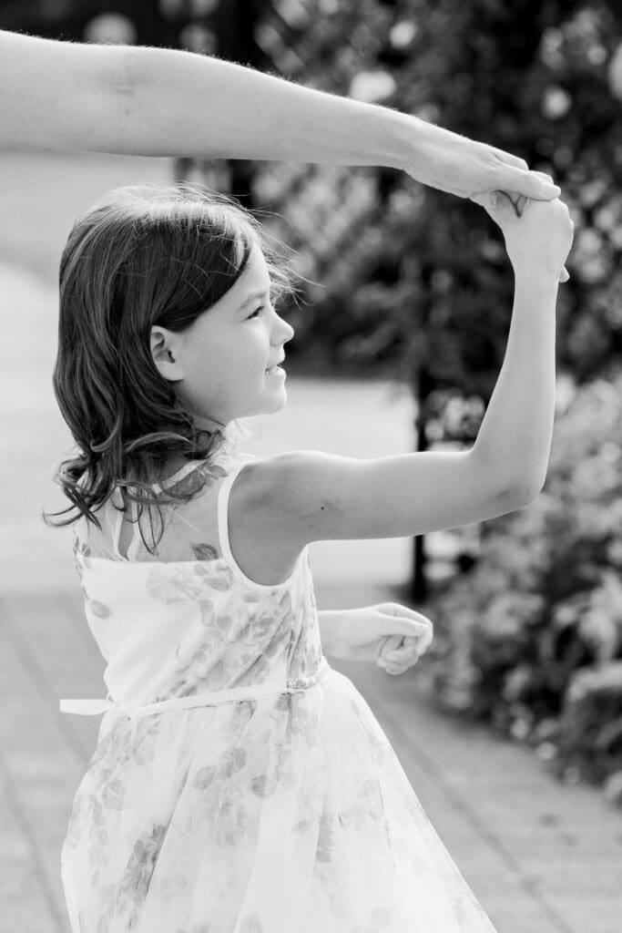 Young girl smiling as she dances during a family photo session at Burlington Botanical Gardens