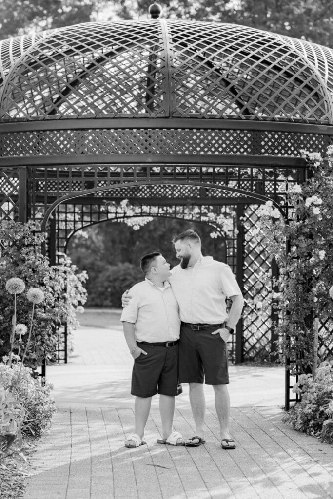 Dad hugging his son with laughter in front of a gazebo during a garden session.