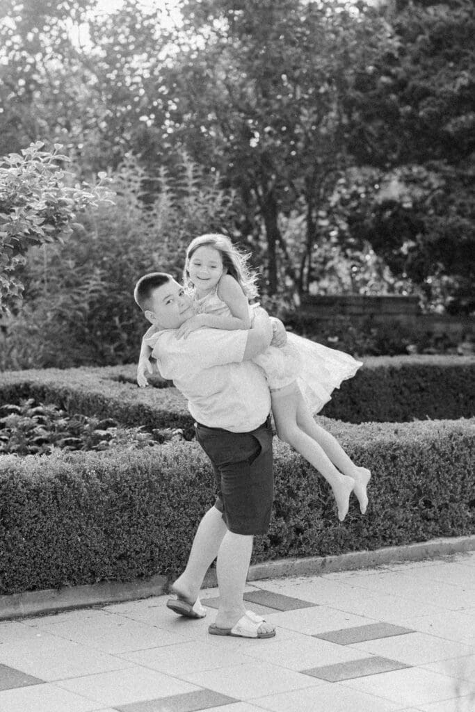 Big brother lifting his sister while laughing together during a family session.