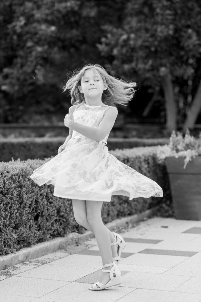 oung girl twirling in a floral dress during a black and white family session portrait.