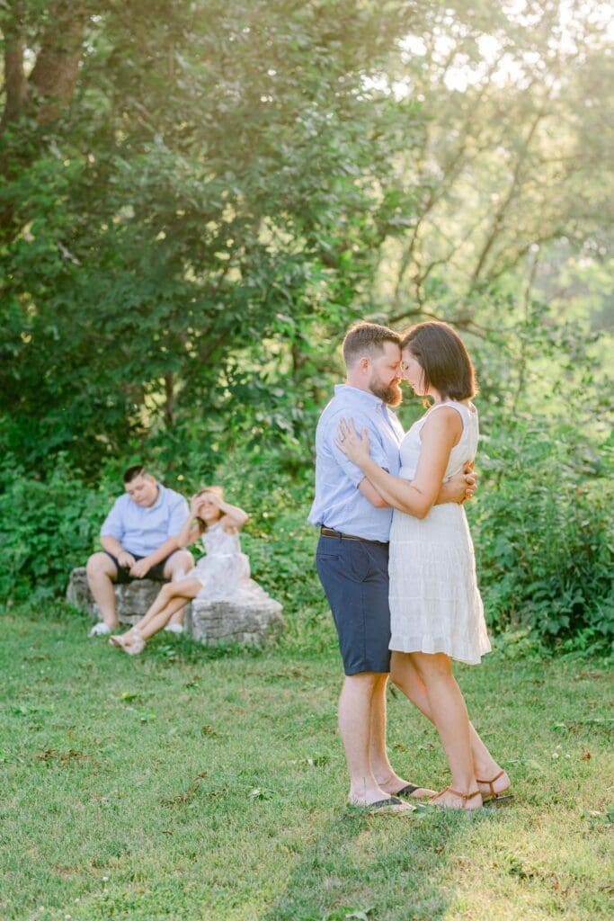 Parents sharing a quiet embrace while children relax in the background during a garden session.