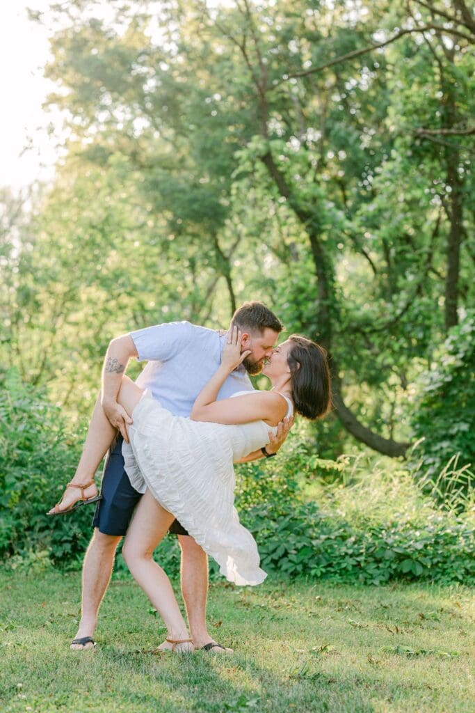 Couple sharing a dip kiss in a sunlit clearing at Burlington Botanical Gardens.