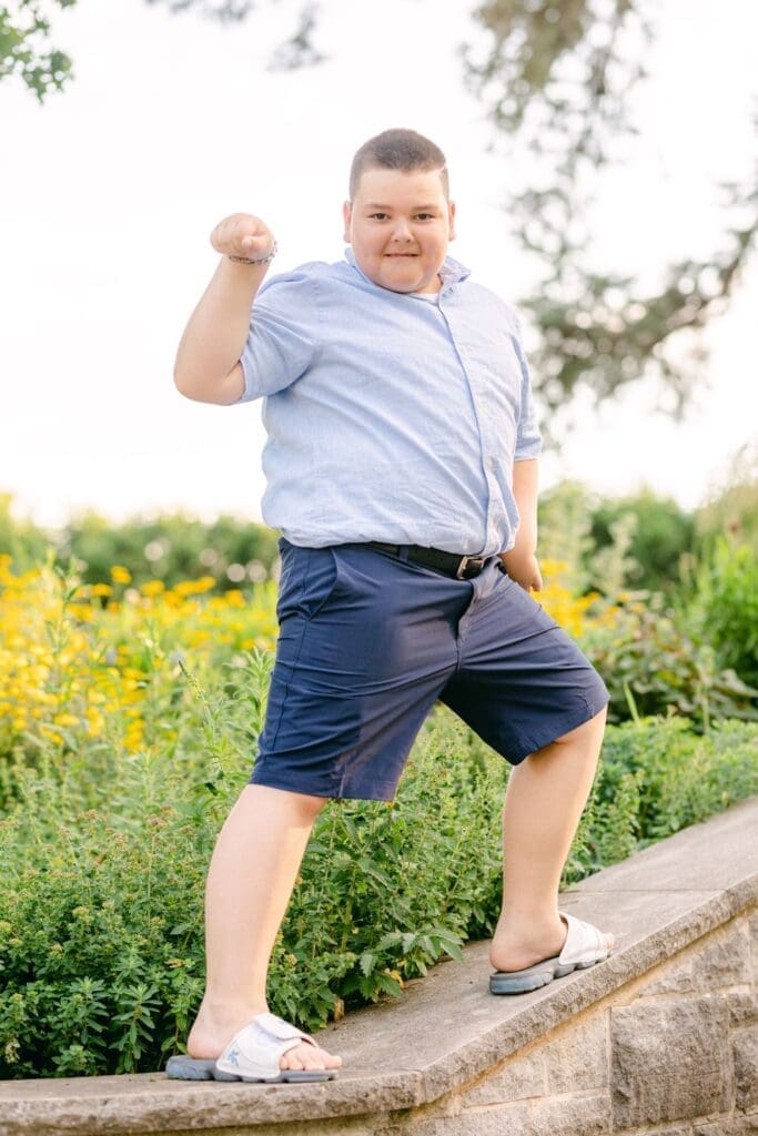 Young boy striking a fun pose in front of yellow wildflowers at Burlington Botanical Gardens.