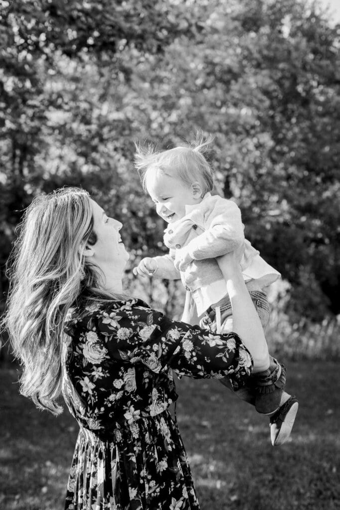 Mom lifts her laughing toddler son into the air during a black and white photo session