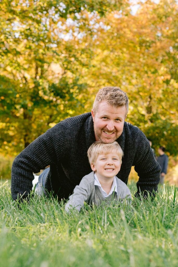 Dad and young boy playing together in the grass during a fall family session