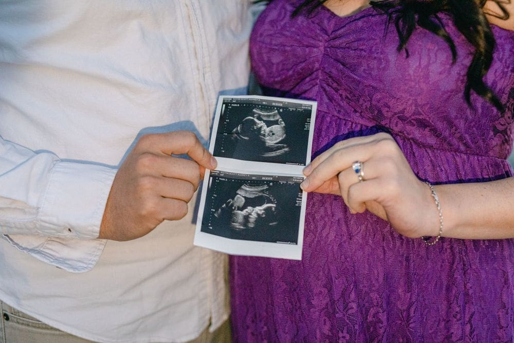 Couple holding ultrasound photos during outdoor maternity session
