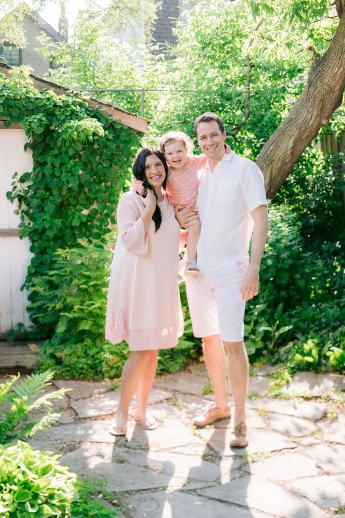 Family of three smiling together in backyard garden