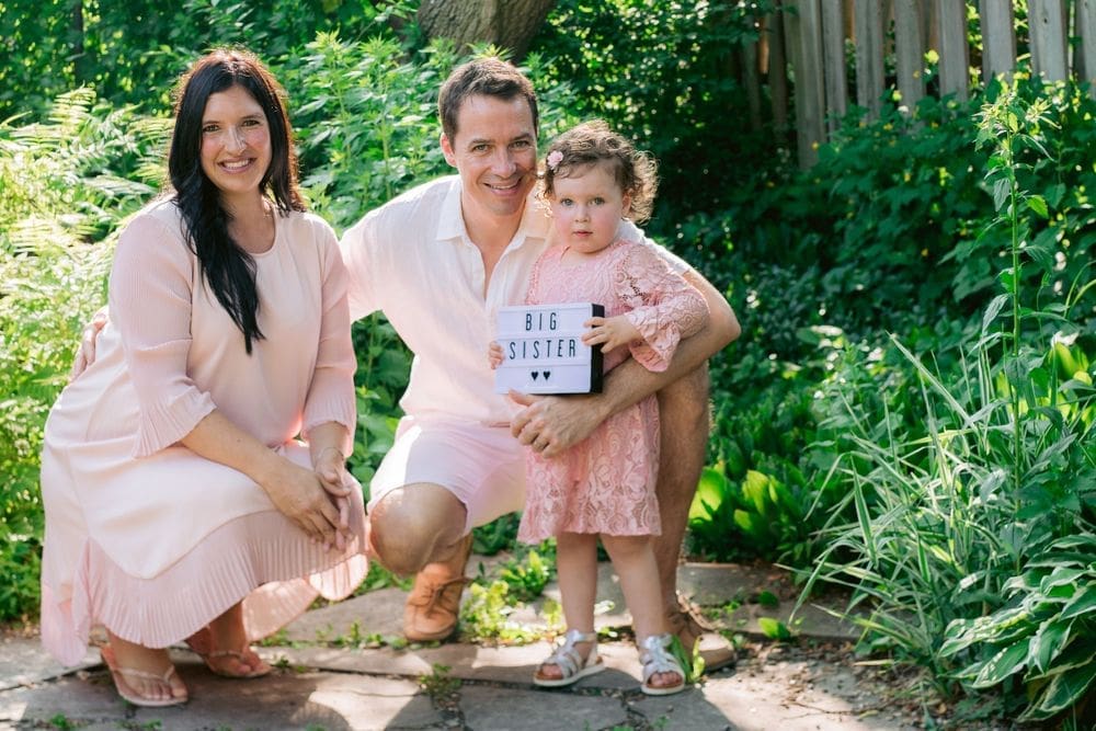 Family announcement with child holding "Big Sister" sign