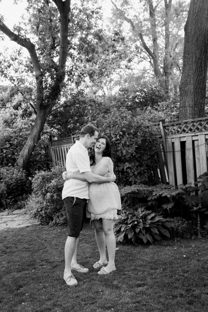 Couple laughing together in their backyard during a maternity session